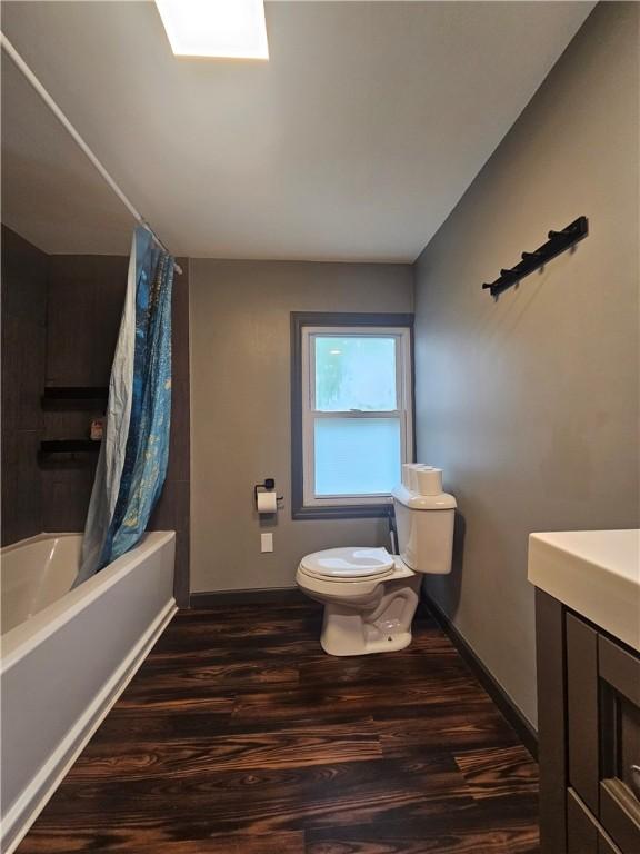 57 Interstate Pkwy, Bradford-City, PA 16701 - bathroom featuring wood finished floors, baseboards, toilet, and shower / tub combo with curtain