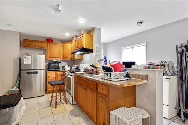 kitchen with freestanding refrigerator, under cabinet range hood, white electric range oven, black microwave, and light tile patterned floors