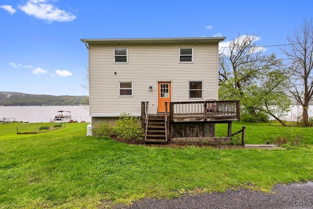 back of property with a deck with water view, a lawn, and stairway