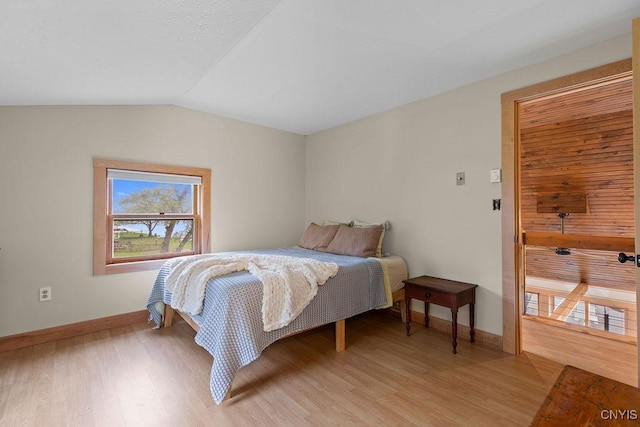 bedroom featuring light wood-type flooring, baseboards, and lofted ceiling