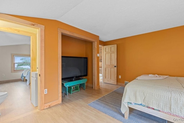 bedroom featuring vaulted ceiling, wood finished floors, and baseboards