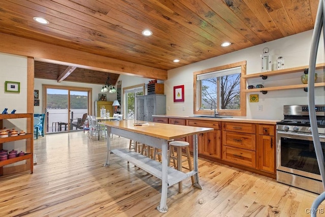 kitchen with stainless steel range with gas stovetop, a sink, wooden ceiling, brown cabinetry, and light countertops