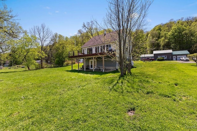 view of green lawn featuring a deck and a wooded view