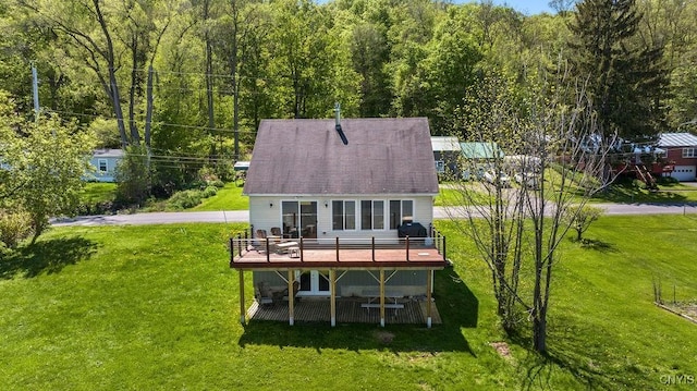 back of property with a wooden deck, a yard, and a forest view