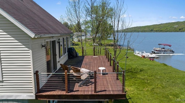 wooden deck with a water view and a lawn