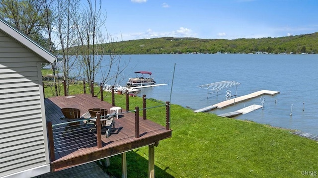 dock area featuring a deck with water view, a forest view, and a yard
