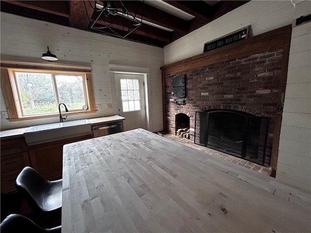 93 Main St, Laurens, NY 13796 - kitchen featuring a sink, a brick fireplace, light countertops, wood walls, and beam ceiling