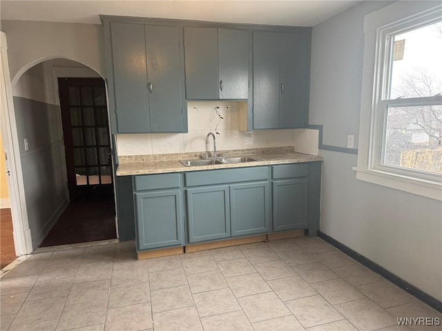 231 Grider St, Buffalo, NY 14215 - kitchen featuring a sink, light countertops, arched walkways, blue cabinets, and light tile patterned floors