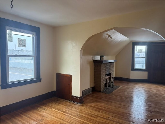 231 Grider St, Buffalo, NY 14215 - unfurnished living room featuring baseboards, wood finished floors, arched walkways, and a fireplace