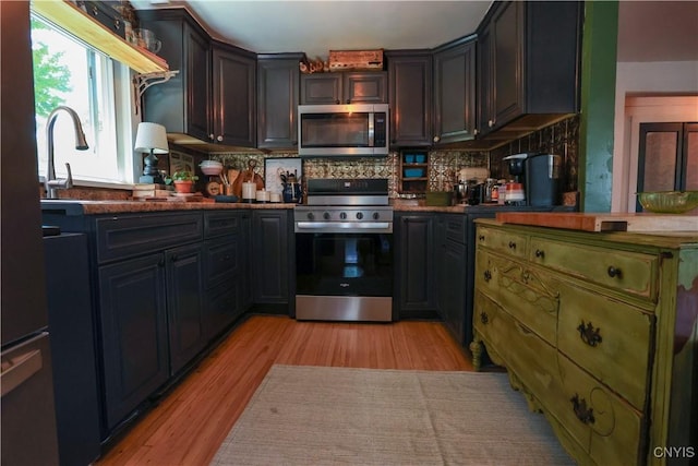 285 Clinton St, Gouverneur, NY 13642 - kitchen with stainless steel appliances, light wood-type flooring, backsplash, a sink, and dark countertops