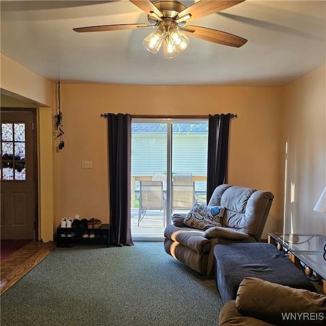 carpeted living area with a ceiling fan