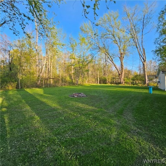 view of green lawn with a fire pit