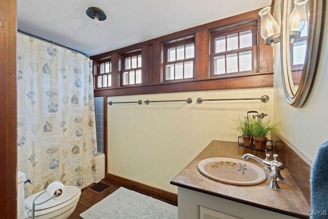 2066 Deerlick Rd, Cape Vincent, NY 13618 - full bathroom featuring toilet, vanity, shower / bathtub combination with curtain, wood finished floors, and baseboards