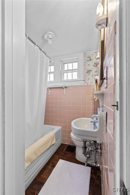 2066 Deerlick Rd, Cape Vincent, NY 13618 - full bathroom with toilet, shower / bathtub combination with curtain, tile walls, and a sink