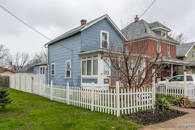 back of house featuring a chimney and a fenced front yard