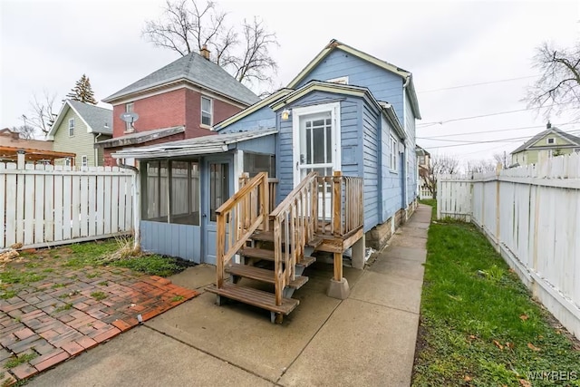 rear view of property with a sunroom, a fenced backyard, and a patio