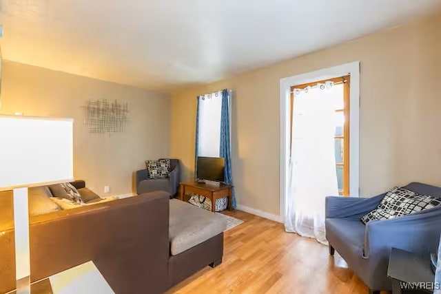 living area featuring light wood-style flooring, baseboards, and plenty of natural light