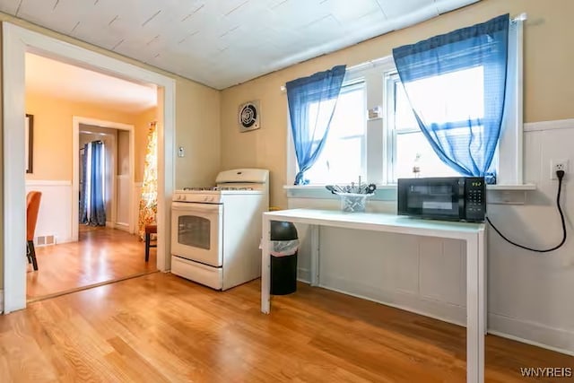 washroom with light wood-style floors and a wainscoted wall