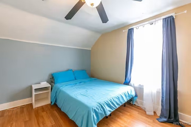 bedroom with vaulted ceiling, wood finished floors, a ceiling fan, and baseboards