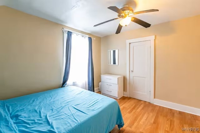 bedroom featuring light wood finished floors, baseboards, and ceiling fan
