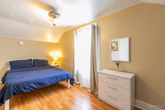 bedroom with vaulted ceiling and light wood-style floors