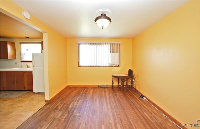unfurnished room with baseboards, wood finished floors, and a sink