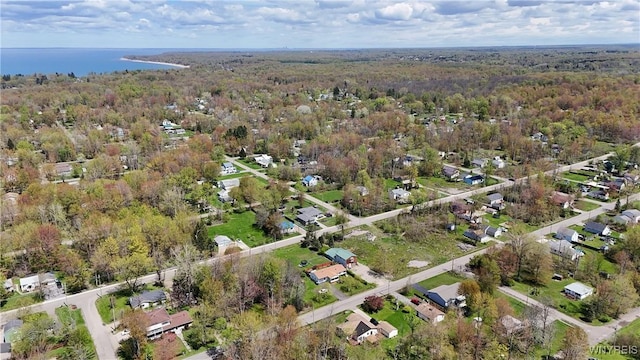 aerial view of property's location featuring a forest, a large body of water, and nearby suburban area