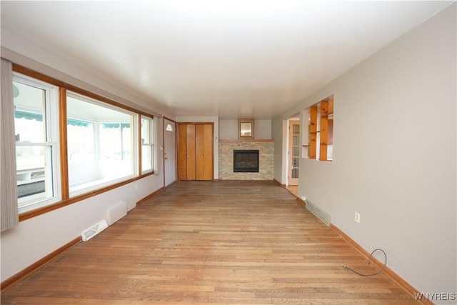 unfurnished living room with light wood-style floors, a glass covered fireplace, and baseboards