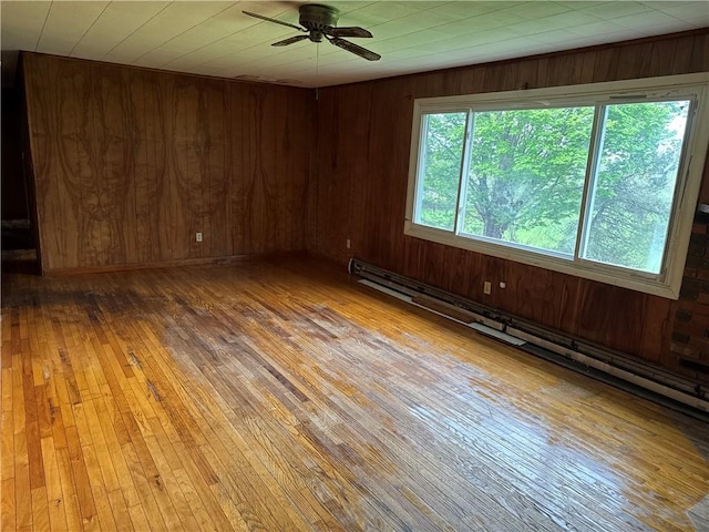 37 Hilltop Dr, Schroeppel, NY 13135 - unfurnished room with light wood-style floors, ceiling fan, wooden walls, and a baseboard heating unit