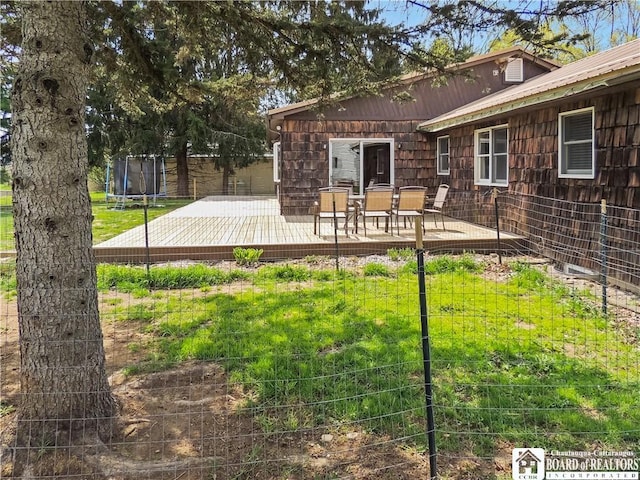 3830 E Ross Mills Rd, Ellicott, NY 14733 - rear view of house featuring a trampoline, a wooden deck, metal roof, and outdoor dining area