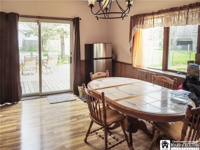 3830 E Ross Mills Rd, Ellicott, NY 14733 - dining area with wainscoting, plenty of natural light, a chandelier, wood finished floors, and wooden walls