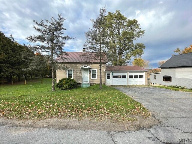 43815 Stine Rd, Alexandria, NY 13679 - view of front of house featuring asphalt driveway, metal roof, a front lawn, and a garage