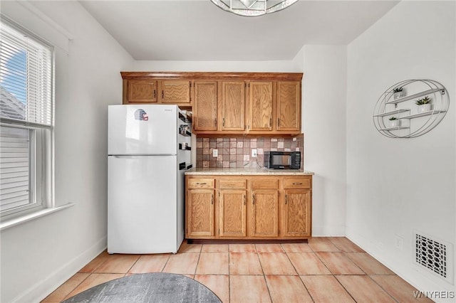 61 Norwalk Ave, Buffalo, NY 14216 - kitchen featuring freestanding refrigerator, black microwave, light countertops, and brown cabinetry