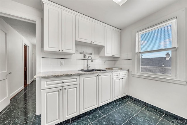 61 Norwalk Ave, Buffalo, NY 14216 - kitchen featuring a sink, white cabinets, baseboards, and light stone counters