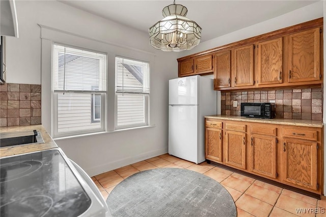 61 Norwalk Ave, Buffalo, NY 14216 - kitchen with freestanding refrigerator, brown cabinetry, decorative backsplash, light tile patterned flooring, and a chandelier