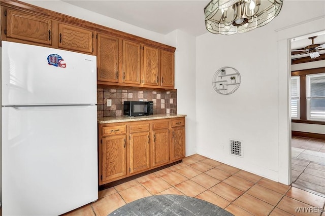 61 Norwalk Ave, Buffalo, NY 14216 - kitchen featuring freestanding refrigerator, black microwave, brown cabinetry, and decorative backsplash