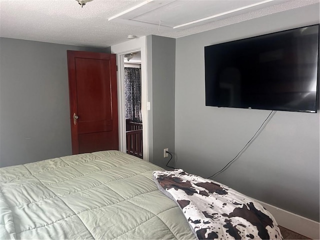 bedroom featuring attic access, a textured ceiling, and carpet floors