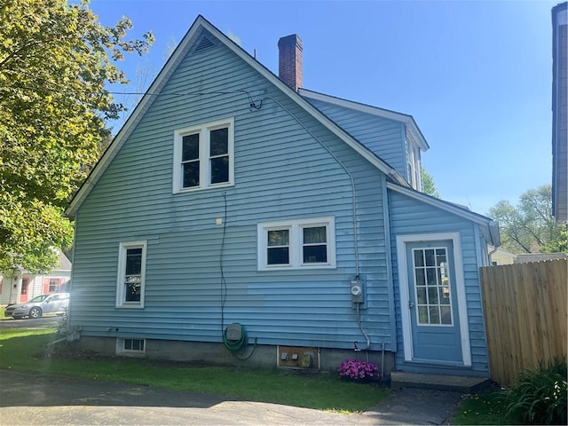 back of property with fence and a chimney