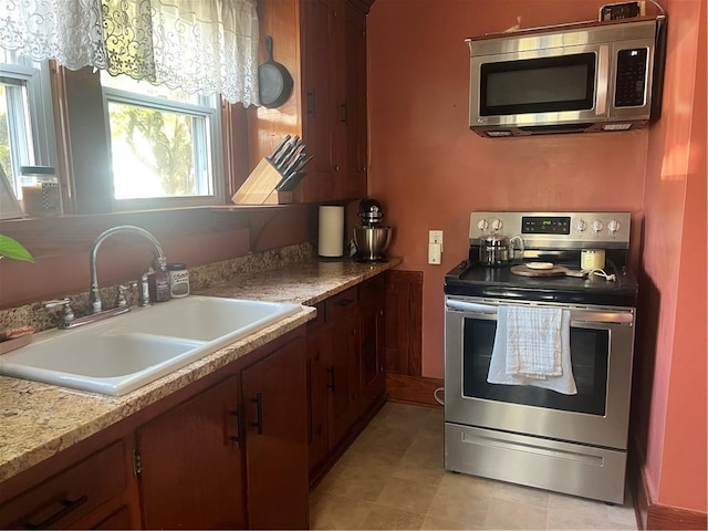 kitchen with appliances with stainless steel finishes, a sink, light countertops, and light tile patterned flooring