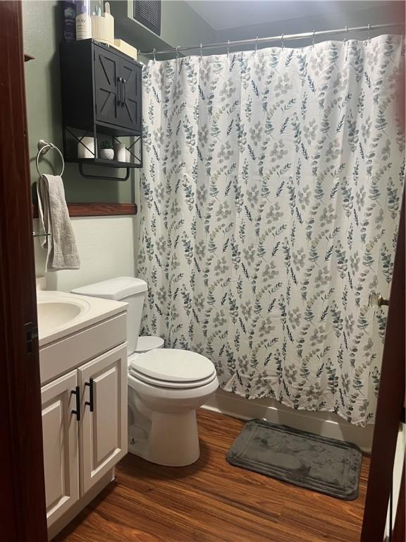full bath featuring wood finished floors, toilet, a shower with shower curtain, and vanity