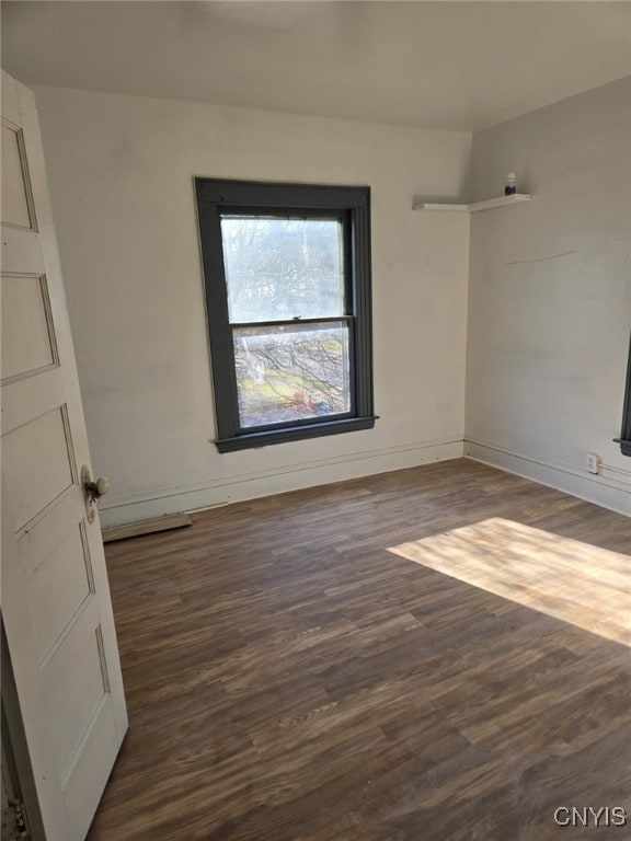 unfurnished room with dark wood-type flooring and baseboards