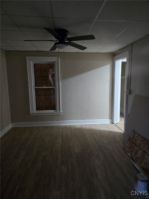 empty room featuring a paneled ceiling, wood finished floors, baseboards, and ceiling fan