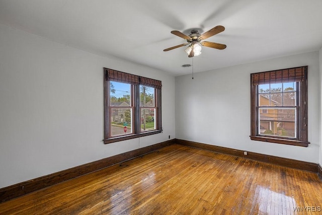 unfurnished room featuring healthy amount of natural light, baseboards, and wood-type flooring