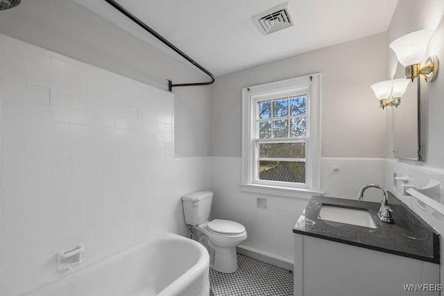 full bathroom with tile walls, toilet, wainscoting, vanity, and tile patterned flooring