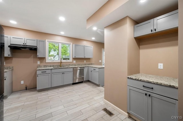 212 N Broad St, Oneida-Inside, NY 13421 - kitchen featuring stainless steel dishwasher, a sink, gray cabinetry, under cabinet range hood, and light stone countertops