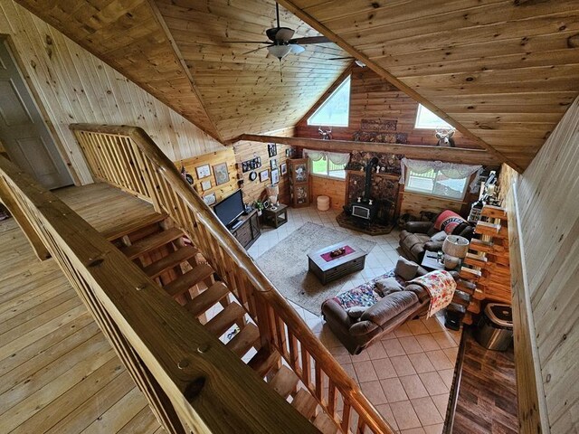 4138 Hubbs Rd, Hector, NY 14818 - living room with wood walls, wood ceiling, a wood stove, a ceiling fan, and tile patterned floors
