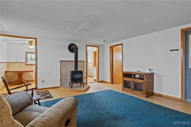 449 Madison Ave, Evans, NY 14006 - living room with a wood stove, a textured ceiling, a ceiling fan, and baseboards