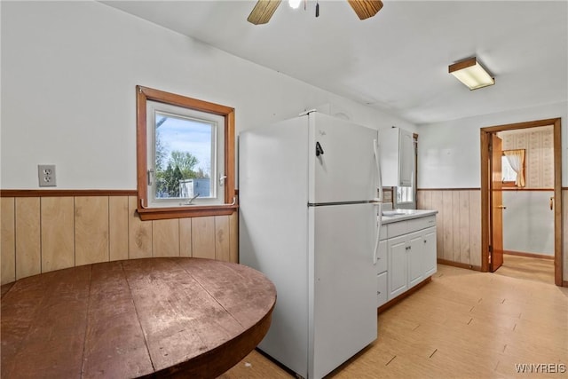 449 Madison Ave, Evans, NY 14006 - kitchen with freestanding refrigerator, wainscoting, wood walls, ceiling fan, and light wood-style flooring