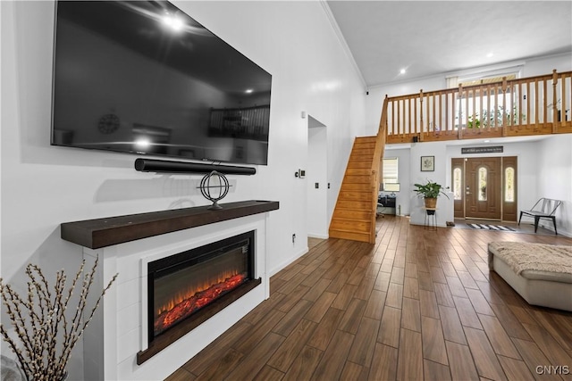 7678 Totman Rd, Cicero, NY 13212 - living room featuring stairway, crown molding, a glass covered fireplace, dark wood-type flooring, and a towering ceiling