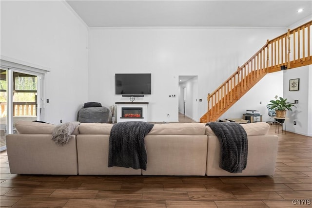 7678 Totman Rd, Cicero, NY 13212 - living area with a high ceiling, stairs, a glass covered fireplace, dark wood finished floors, and crown molding